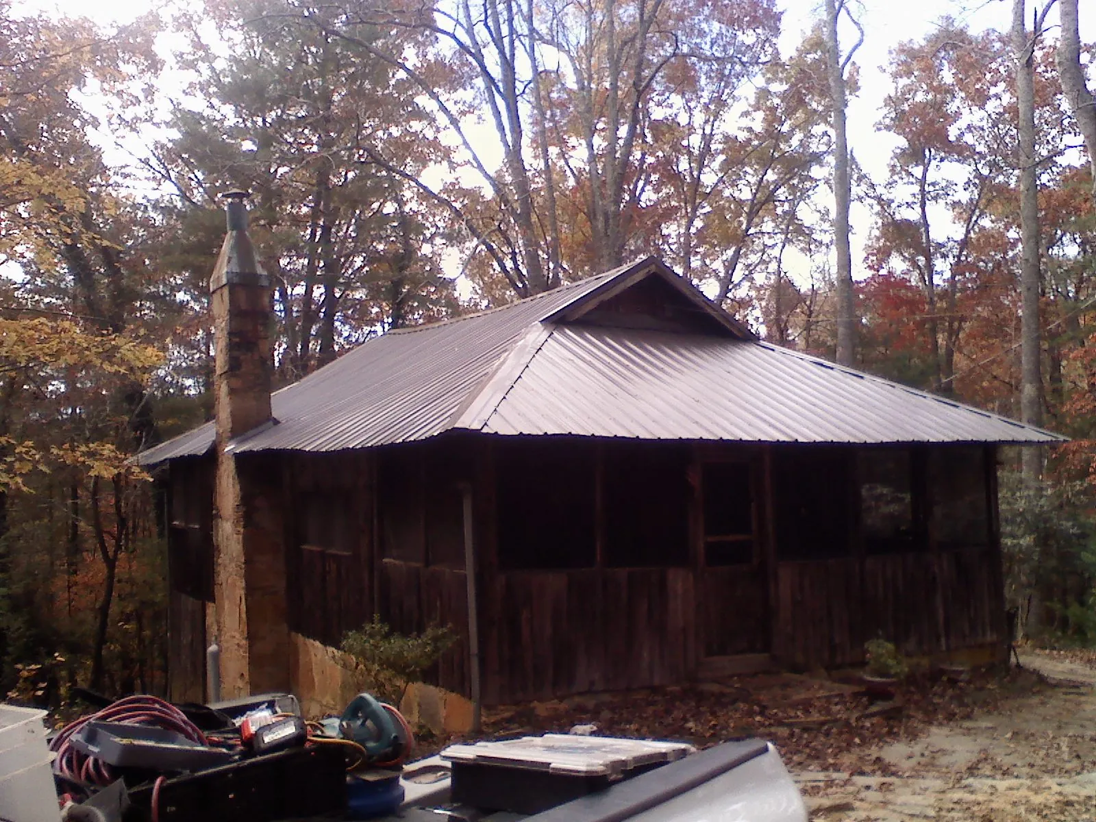 Brown metal hip roof on an old cabin with a stone chimney in Huntley
