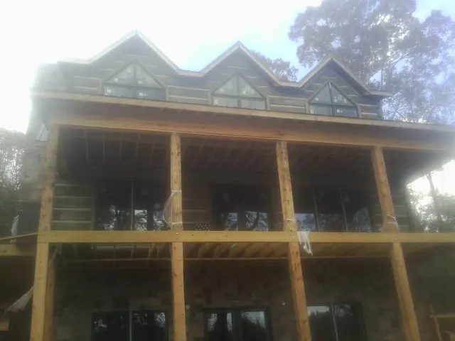 Dormers and porch framing on a large log home under construction — Roof Coating work by our crew in Huntley