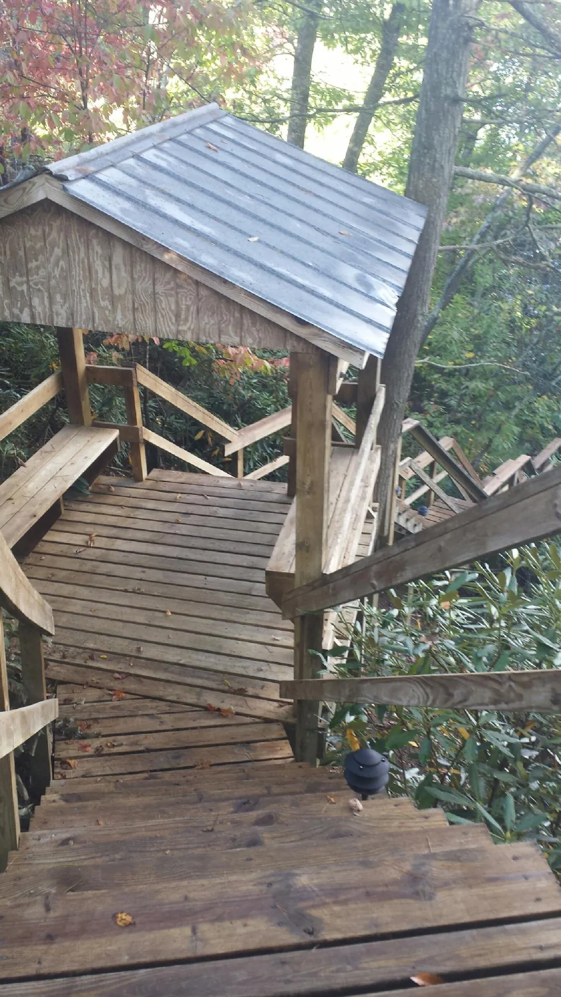 Metal roofed shelter over wooden steps on a wooded walkway — Skylight Repair & Installation work by our crew in Huntley