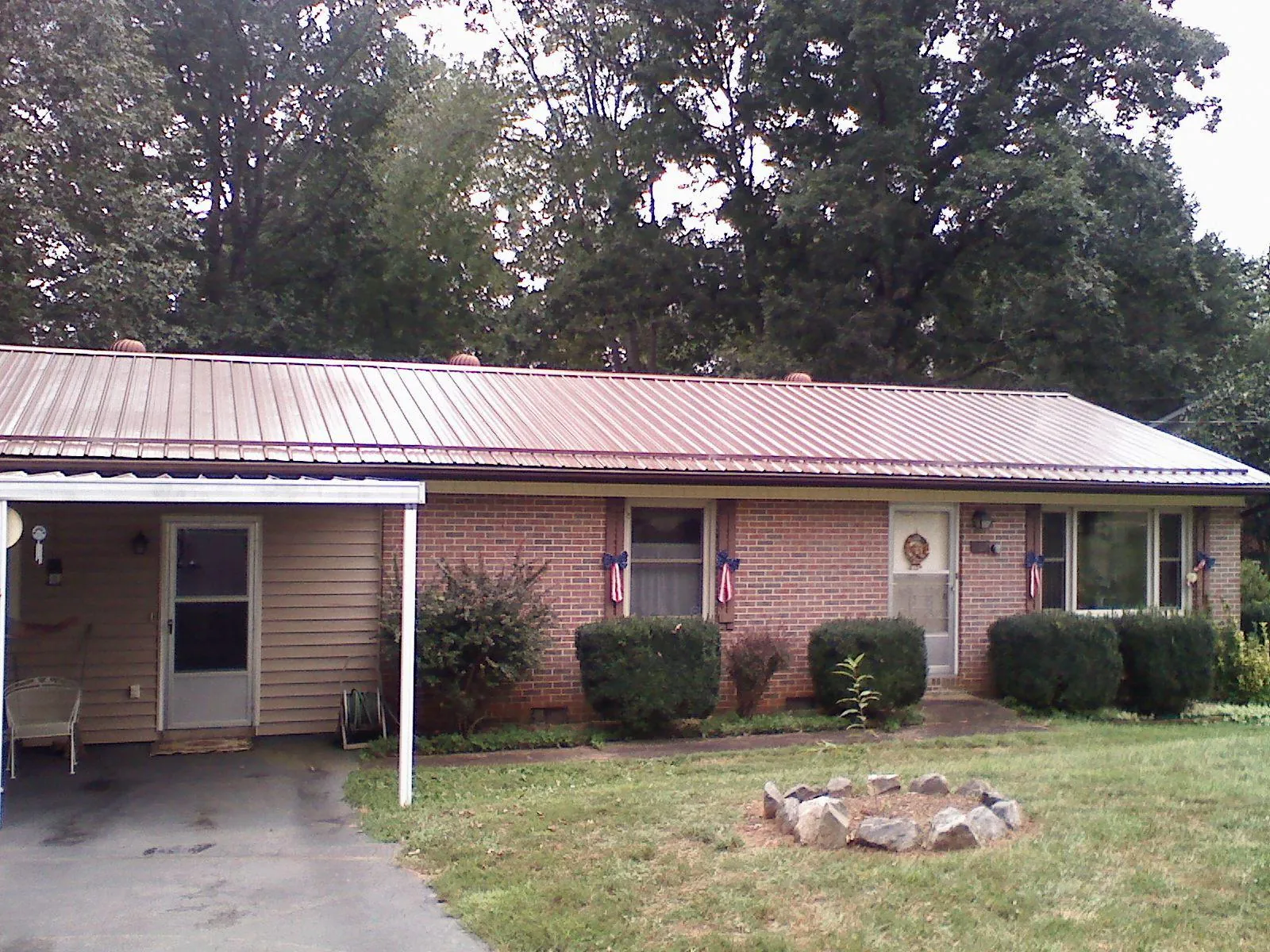 Bronze metal roof and carport on a brick ranch home — Roof Repair work by our crew in Huntley